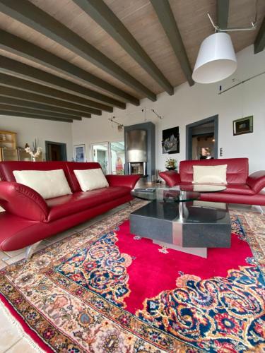 a living room with a red couch and a red rug at Wunderschönes Ferienhaus mit Fernblick, unweit von Limburg und Rhein-Main-Gebiet in Hünfelden
