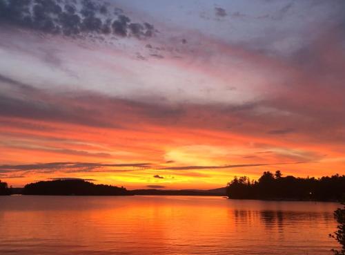 a sunset over a body of water with trees at Cottage 4 - 1 Bed w/ Loft / 1 Bath & Courtyard in Wolfeboro