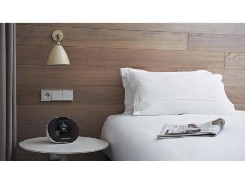 a bed with a remote control and a magazine on a table at 9Hotel Opera in Paris