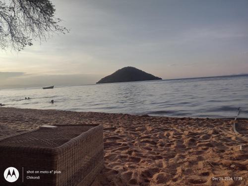 a sandy beach with a small island in the water at Quest at Cape Maclear in Chembe