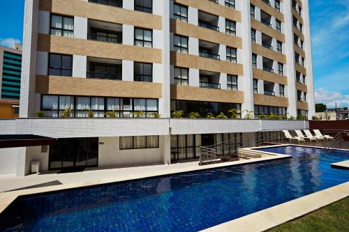 un hôtel avec une grande piscine en face d'un bâtiment dans l'établissement Comfort Hotel & Suites Natal, à Natal