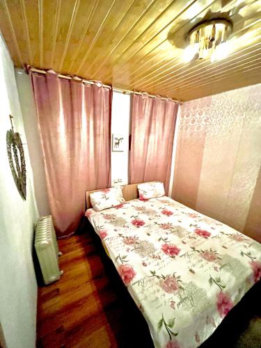 a small bedroom with a bed with pink curtains at Cabană B&M in Slănic-Moldova