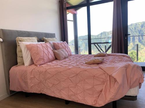ein Bett mit einer rosa Decke in einem Zimmer mit einem Fenster in der Unterkunft Ginjas Mountain Houses in São Vicente