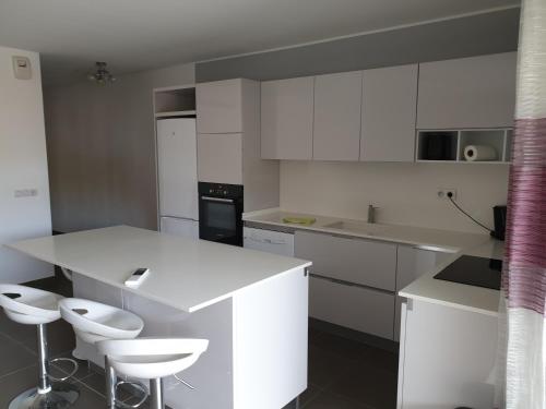 a kitchen with white cabinets and white stools at T2 55 m2 4 pers jacuzzi terrasse 55m2 in Ficaja