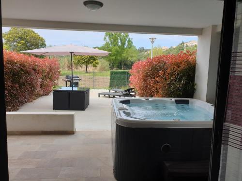 a hot tub in a patio with an umbrella at T2 55 m2 4 pers jacuzzi terrasse 55m2 in Ficaja