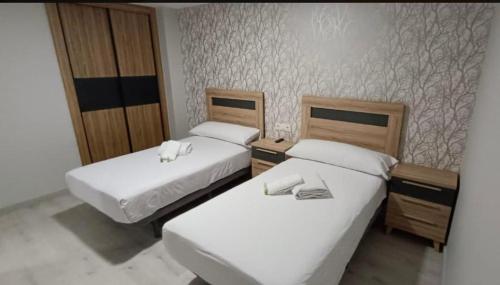 two beds in a hotel room with white sheets at O nido do cuco in Muxia