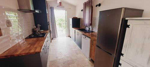 La cuisine est équipée d'un réfrigérateur en acier inoxydable et de comptoirs en bois. dans l'établissement Studio charmant avec piscine partagée à Draguignan, 42 m², à Draguignan