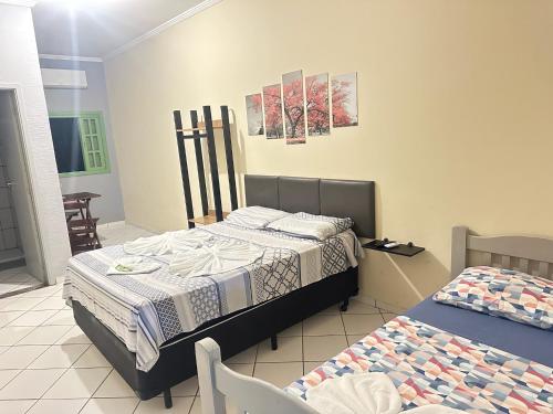 a bedroom with two beds and a table and chairs at Pousada Meraki Beach in Caraguatatuba