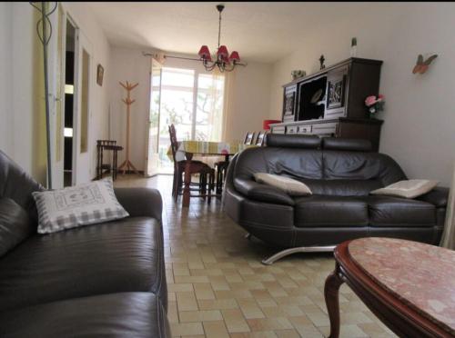 un salon avec un canapé en cuir noir et une table dans l'établissement Villa la Galine, à Puimisson