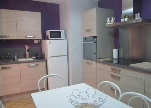 une cuisine avec une table et un réfrigérateur blanc dans l'établissement Villa la Galine, à Puimisson