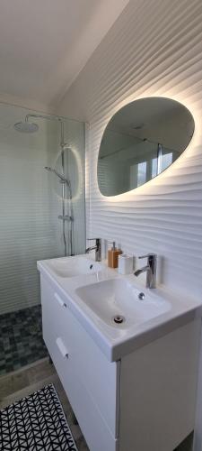 une salle de bain blanche avec un lavabo et un miroir dans l'établissement Maison Cosy Coco 1h Paris et 2h plages Normandie, à Broué