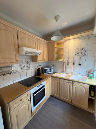 a kitchen with wooden cabinets and a sink at Escapade Familiale - parking privé - 25 min de Bâle in Mulhouse