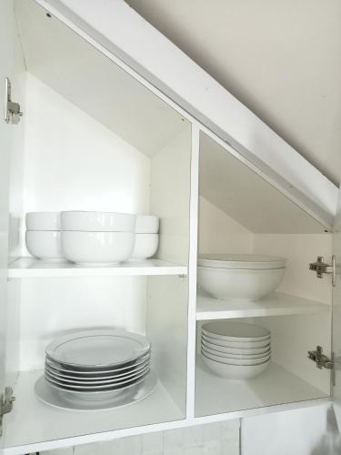 a white cabinet with plates and bowls in it at Anagata House Batu at C8 Grand Kusuma Hill in Batu