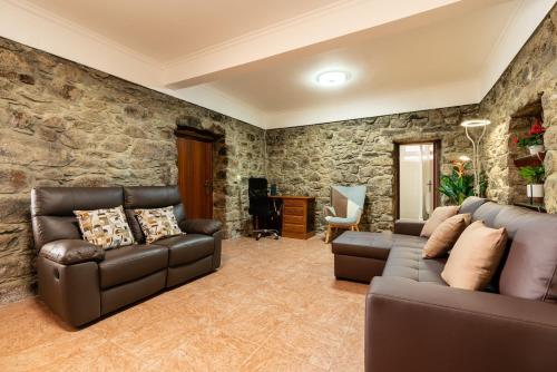 a living room with two couches and a stone wall at Sunset House in Calheta