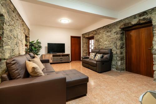 a living room with a leather couch and a television at Sunset House in Calheta