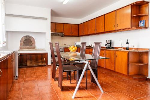 a kitchen with wooden cabinets and a table and chairs at Sunset House in Calheta