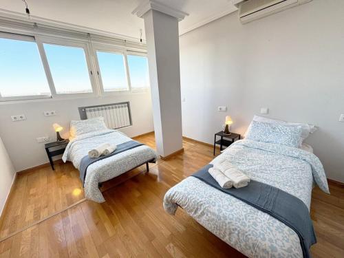 two beds in a room with two windows at Madrid Luxe Oasis 4 Bedroom with Terrace & Pool in Torrejón de Ardoz