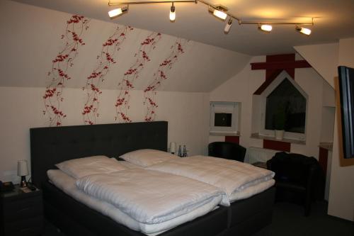 a bedroom with a large bed with white sheets at Landgasthaus Hotel Wolters in Kerken