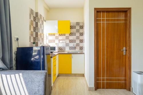a kitchen with yellow cabinets and a blue refrigerator at Housr Charlie, HSR Layout Bengaluru in Bengaluru