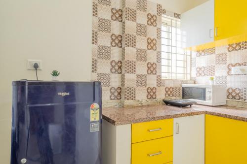 a kitchen with a black refrigerator and yellow cabinets at Housr Charlie, HSR Layout Bengaluru in Bengaluru