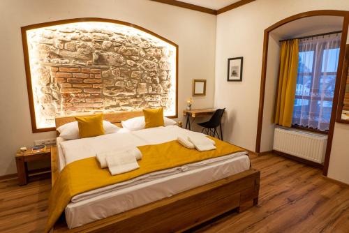 a bedroom with a large bed with a stone wall at Penzión Kolkáreň in Stará Ľubovňa