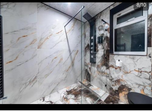 a glass shower in a bathroom with a marble wall at MyNites in Birmingham