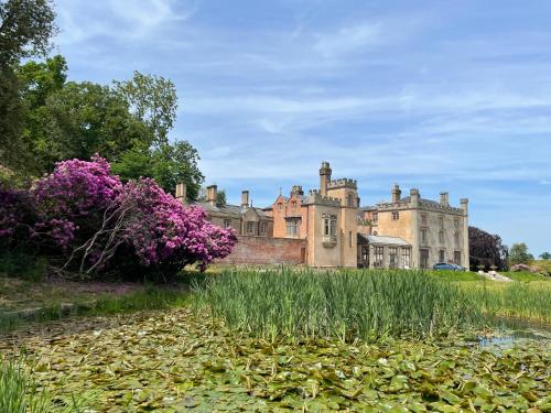 an old castle with purple flowers in front of it at Apartment at Llanerchydol Hall in Welshpool