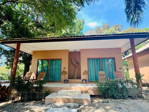 a small house with green shuttered windows and chairs at Sunny Cove Beach Resort Koh Phayam in Ranong
