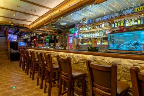 a bar with a row of chairs and a fish tank at Penzión Kolkáreň in Stará Ľubovňa
