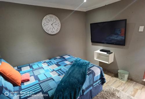 a bedroom with a bed and a clock on the wall at Fresh Ideas GuestHouse in Soshanguve