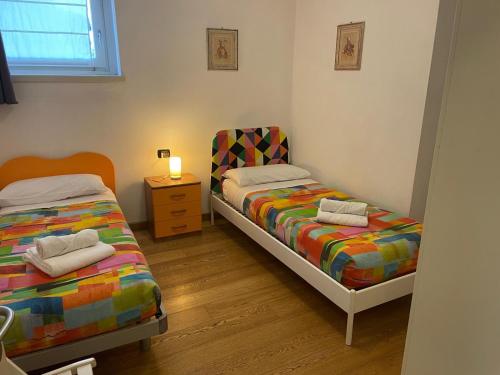 sypialnia z 2 łóżkami i stolikiem nocnym z lampką w obiekcie La Supernova w Bergamo