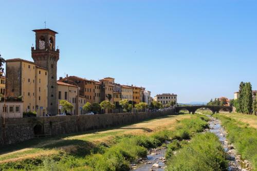 a river in a city with buildings and a clock tower at Claudia's Home La Suite in Pescia