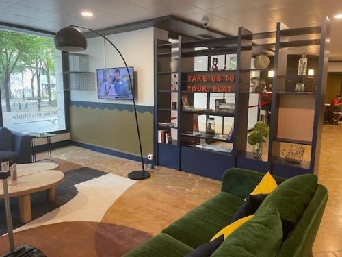 un salon avec un canapé vert et une table dans l'établissement ApparthotelParisDefenseArenaElyseeEiffel, à Courbevoie