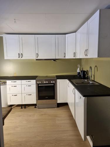 a kitchen with white cabinets and a black counter top at Tortveit 35 in Veum