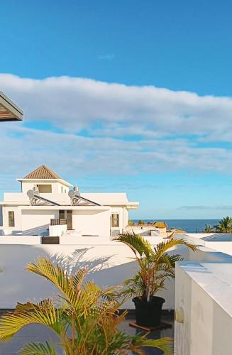 a white house with palm trees in front of the ocean at 3bed villa with private pool and rooftop with a sea view in flic-en-flac, Mauritius in Flic-en-Flac