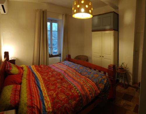 - une chambre avec un lit et une couverture colorée dans l'établissement Maison rose, à Capestang