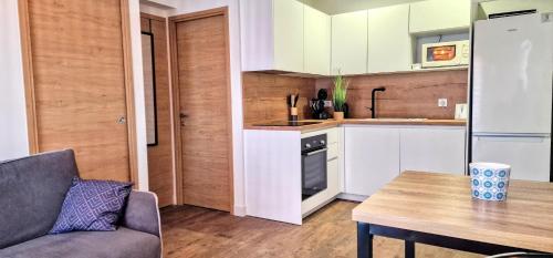 une cuisine avec des armoires blanches et une table dans une pièce dans l'établissement UNIQUE appartement direct PLAGE COMMERCES PARKING PRIVEE CLIM NEUF WIFI, à Banyuls-sur-Mer