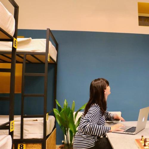 a woman sitting at a desk with a laptop at Scary Hostel in Tbilisi City
