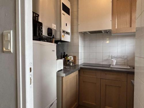 La cuisine est équipée d'un réfrigérateur blanc et de placards en bois. dans l'établissement Appartement Studio BANYULS SUR MER BN070-197, à Banyuls-sur-Mer