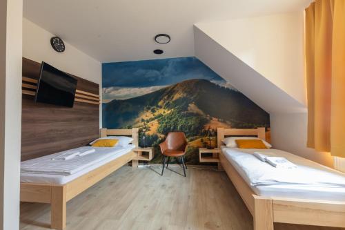 two beds in a room with a mountain mural at Penzión Esprit in Sučany