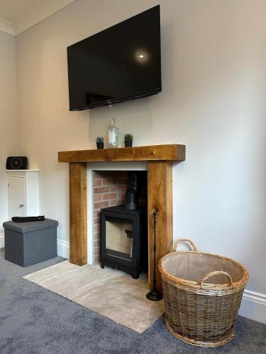a living room with a fireplace with a flat screen tv at Poppy Cottage, Mawdesley Village in Mawdesley