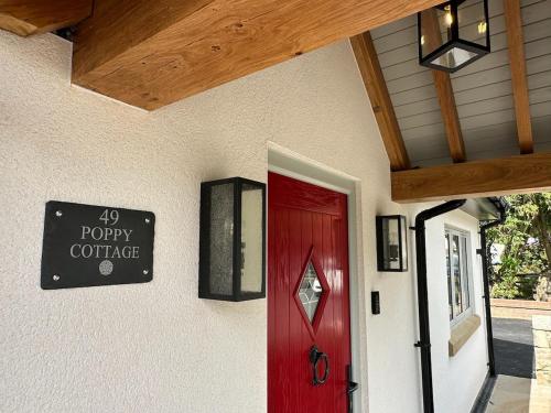 a red door and a sign on a house at Poppy Cottage, Mawdesley Village in Mawdesley