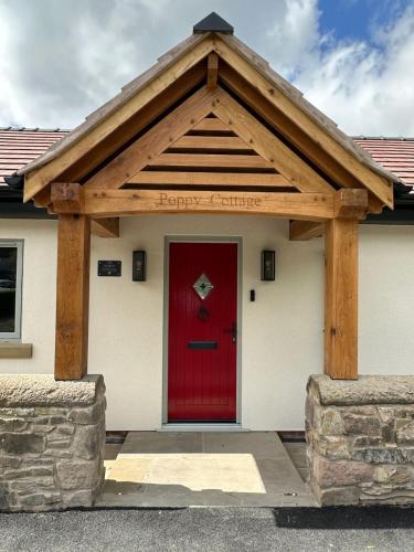 a red door on a building with a wooden roof at Poppy Cottage, Mawdesley Village in Mawdesley