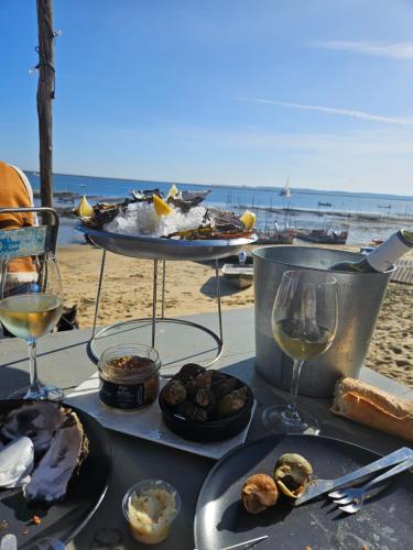 Una mesa con platos de comida y vino en la playa. en Mobil - home ombragé Lege Cap ferret, en Lège-Cap-Ferret