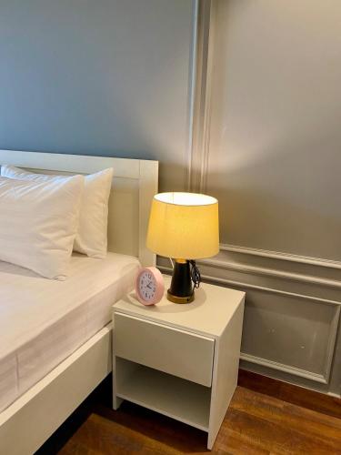 a bed with a nightstand with a lamp and a clock at SUPERHOST Apartments - Near GPO & Mall Road in Murree