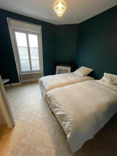 - une chambre avec 2 lits et un mur vert dans l'établissement Maison Jean-Pierre, à Magenta