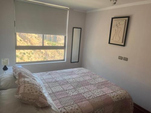a bedroom with a bed with a quilt and a window at Parque Mirador II - 3 Dormitorios - Excelente vista in Viña del Mar