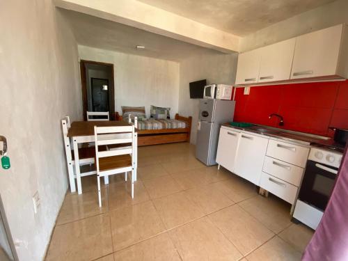 a kitchen with red cabinets and a table and a room at BOA VIDa in Punta Del Diablo