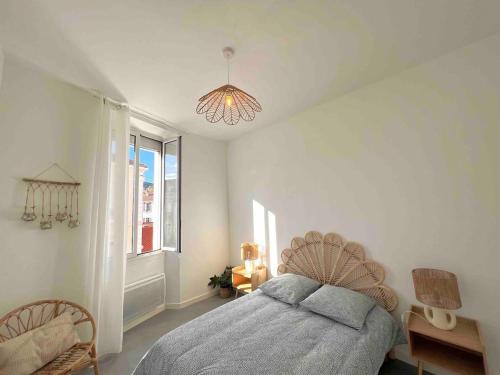 une chambre avec un lit, une fenêtre et un lustre dans l'établissement Appartement lumineux proche gare, à Hyères