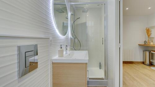 a white bathroom with a sink and a mirror at Le Brière - Appart'Escale in Saint-Nazaire